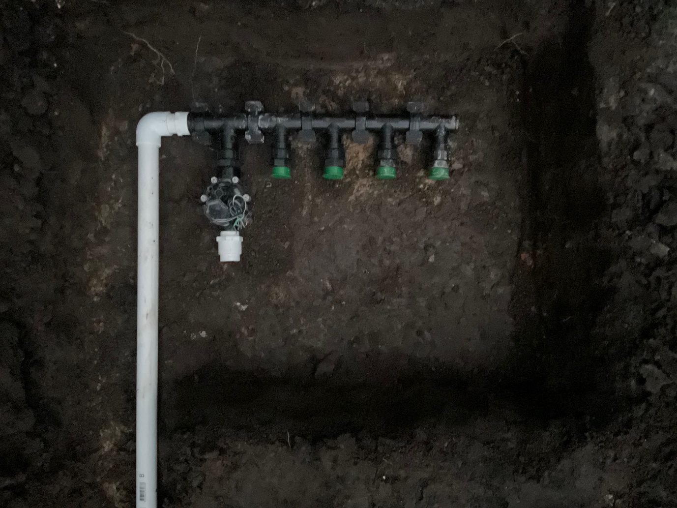 PVC irrigation manifold with five green valves