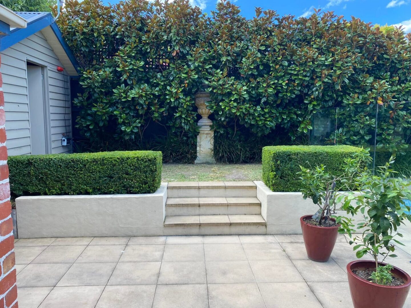 Patio with steps, urn, hedges, potted plants