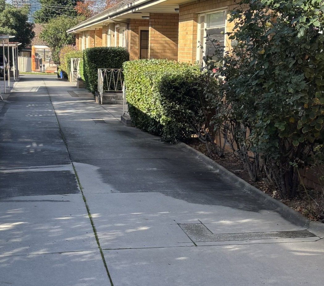 Sunlit apartment walkway with trimmed hedges